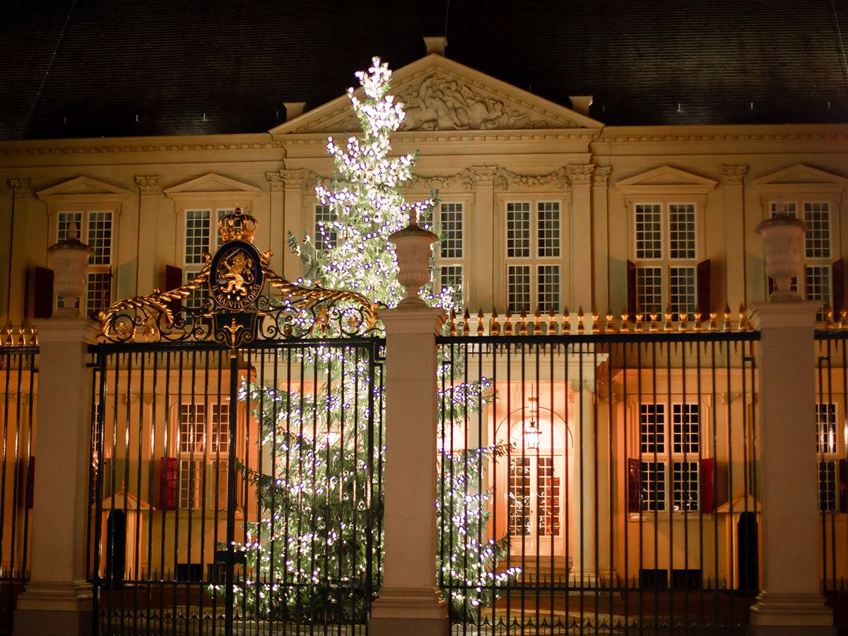 Majestätischer Königspalast bei Nacht mit einem großen, beleuchteten Weihnachtsbaum und einem goldenen Tor.