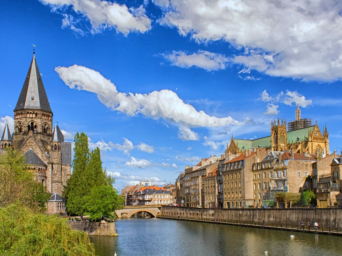 Panoramablick auf Metz mit dem Temple Neuf, Mosel, historischen Gebäuden und der Kathedrale unter blauem Himmel.