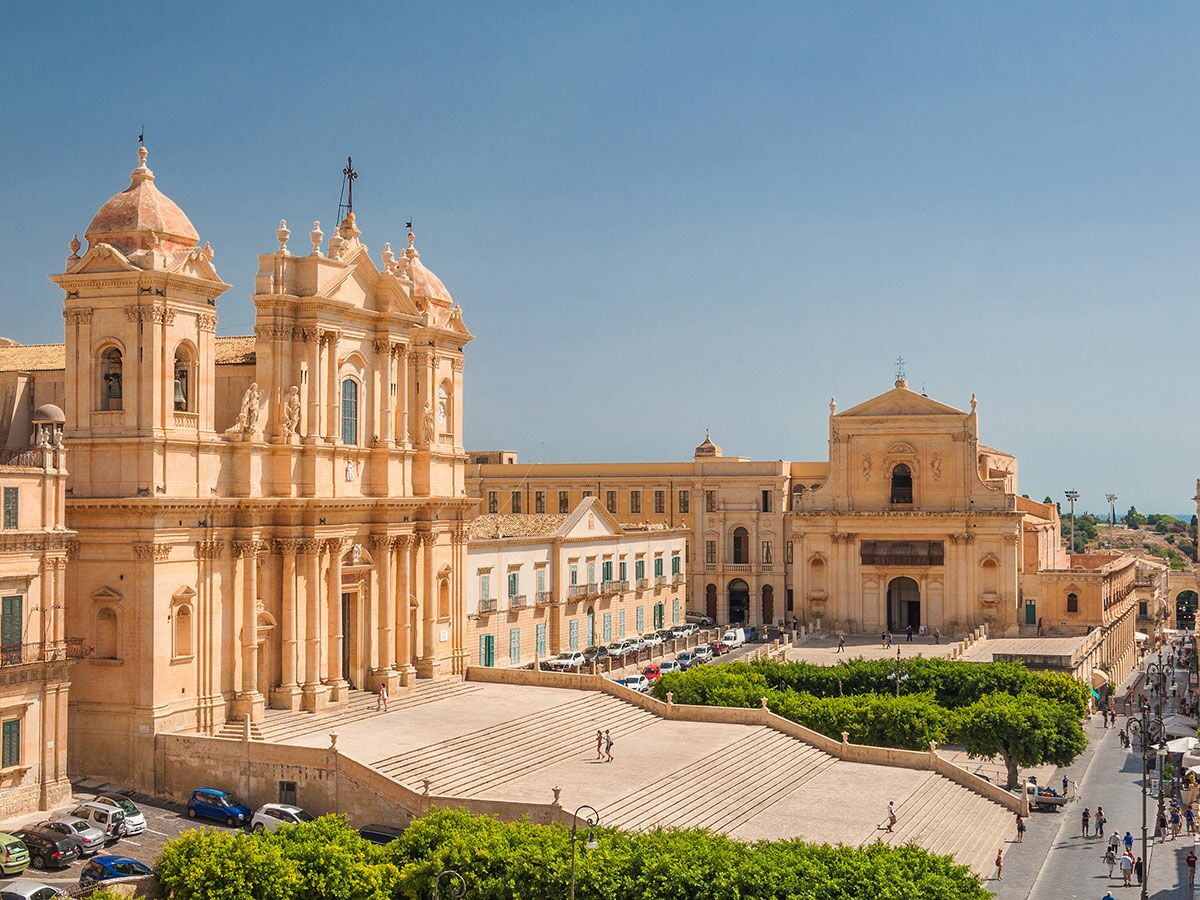 Panoramablick auf die prächtige Noto Kathedrale und den Domplatz mit Menschen unter blauem Himmel in Sizilien, Italien.