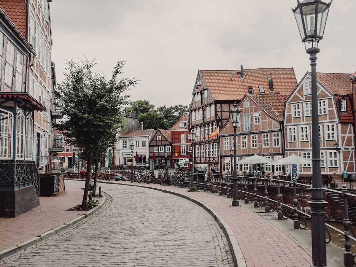 Kopfsteinpflastergasse mit historischen Fachwerkhäusern, Kanal und Straßenlaternen in einer charmanten Altstadt.