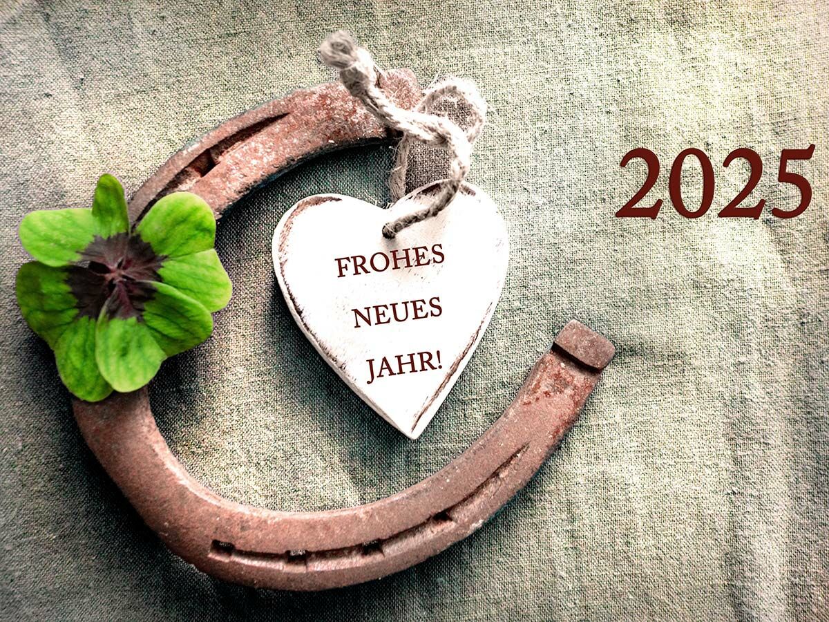 Ein Hufeisen mit vierblättrigem Kleeblatt und einem Herzanhänger „Frohes Neues Jahr!“ sowie der Jahreszahl 2025.