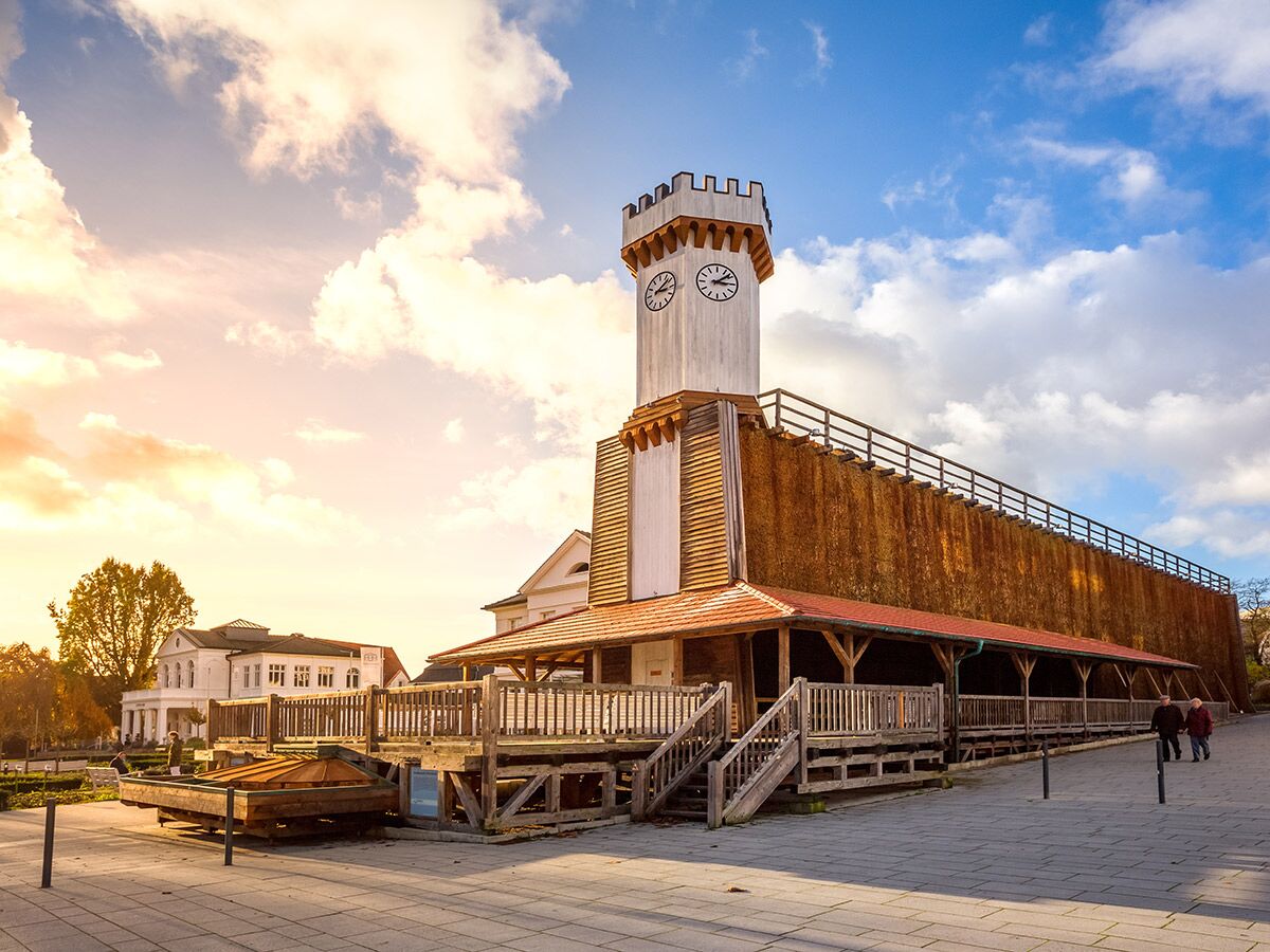 Historisches Gradierwerk in Bad Rothenfelde mit markantem Uhrenturm unter einem lebhaften Himmel bei Sonnenuntergang.
