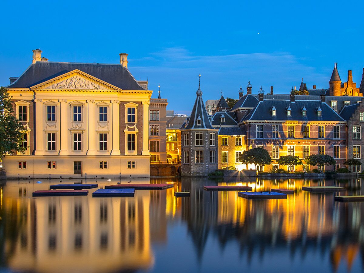 Beleuchteter Binnenhof mit Mauritshuis in Den Haag bei Dämmerung, Spiegelung im Hofvijver See.