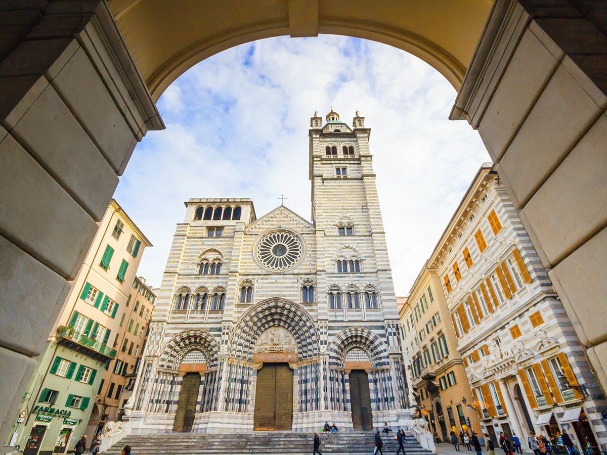 Grandiose Genua Kathedrale San Lorenzo, umrahmt von einem Bogen, mit schwarz-weiß gestreifter Fassade und Glockenturm.