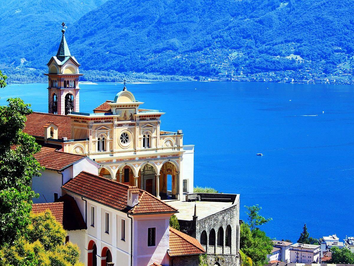 Panoramablick auf die Wallfahrtskirche Madonna del Sasso in Locarno am Lago Maggiore mit Bergen und blauem See.