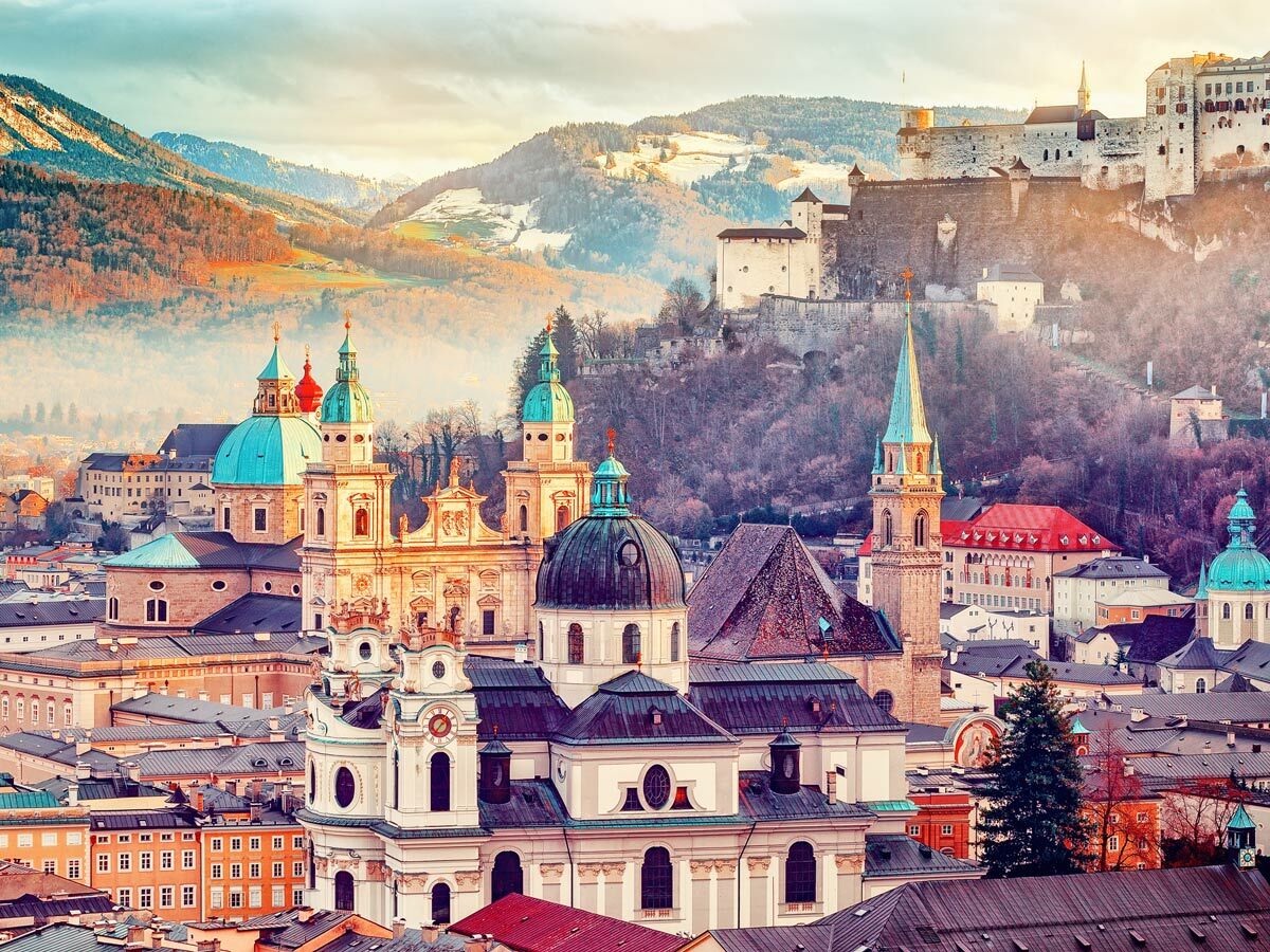 Panorama von Salzburg mit barocken Kirchen, Altstadt und Festung Hohensalzburg vor herbstlichen Alpen.