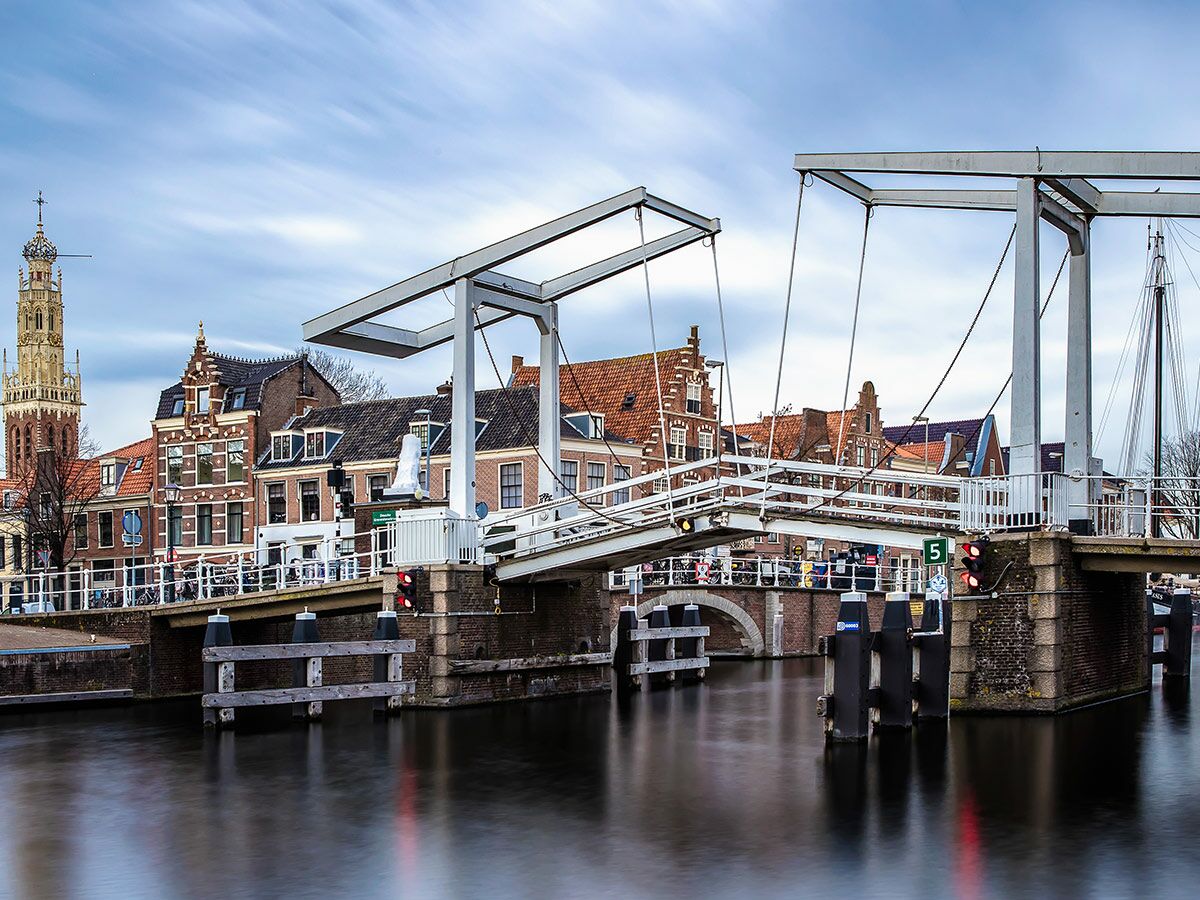 Historische Zugbrücke in Hoorn, Niederlande, geöffnet über einem Kanal, mit traditionellen Häusern und Kirchturm im Hintergrund.