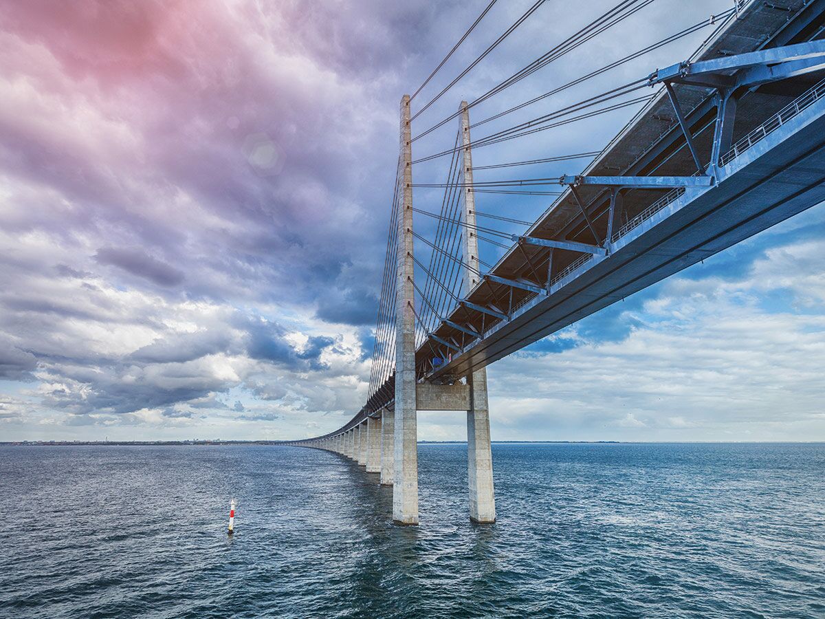 Die imposante Öresundbrücke über dem Meer zwischen Dänemark und Schweden bei dramatischer Bewölkung mit teilweise rosafarbenem Himmel.