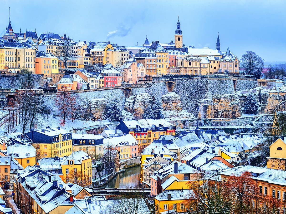 Panoramablick auf das schneebedeckte Luxemburg Stadt im Winter mit bunten Häusern, Fluss, Brücken und historischen Gebäuden und Kirchen.