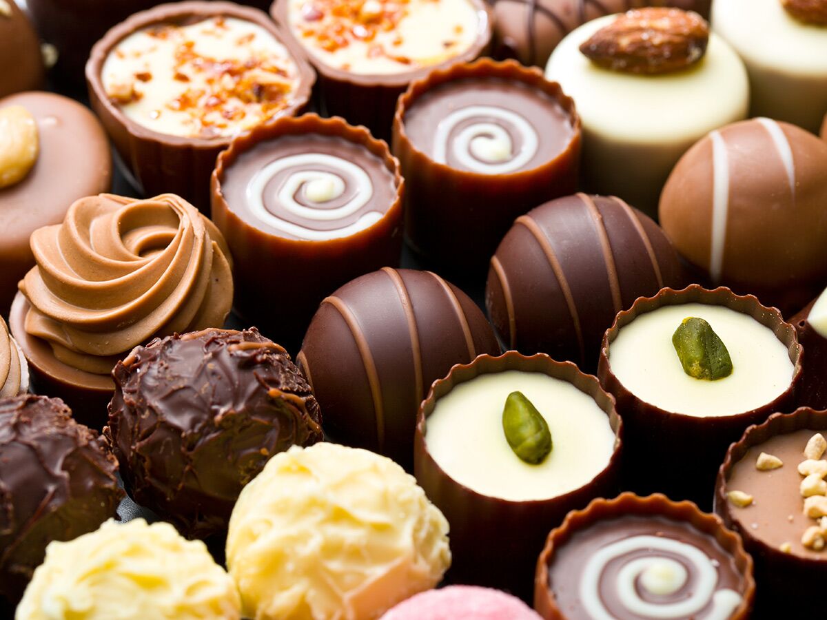Nahaufnahme einer reichhaltigen Auswahl an handgemachten Pralinen und Trüffeln in verschiedenen Formen und Farben, appetitlich angerichtet.