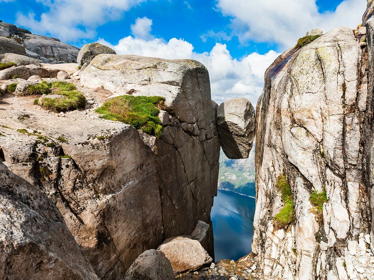 Kjeragbolten Felsbrocken zwischen zwei Klippen über dem Lysefjord in den norwegischen Bergen bei blauem Himmel.