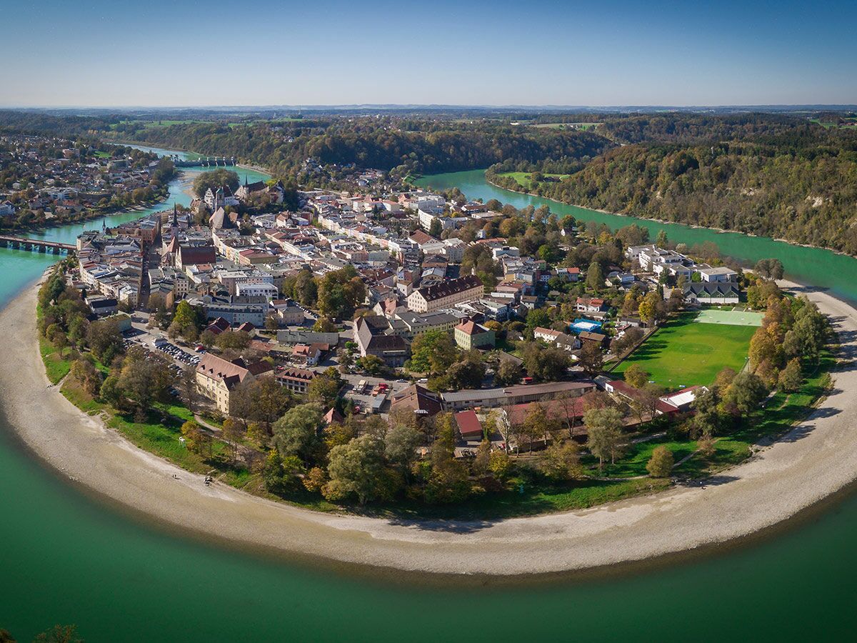 Luftbild von Wasserburg am Inn: Altstadt auf einer Halbinsel am grünen Fluss Inn, umgeben von Wäldern.