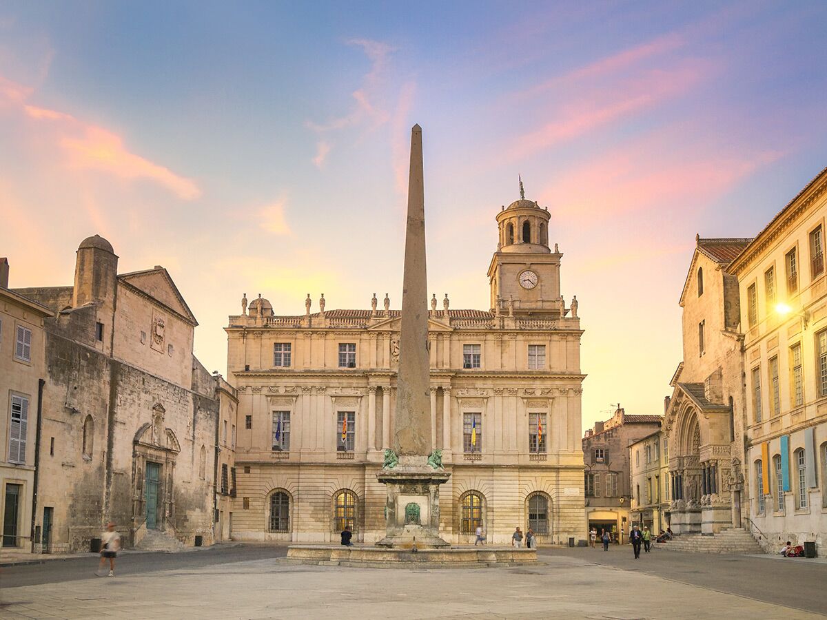 Blick auf den Place de la République in Arles, Frankreich, bei Sonnenuntergang, mit einem ägyptischen Obelisken und dem Rathaus.