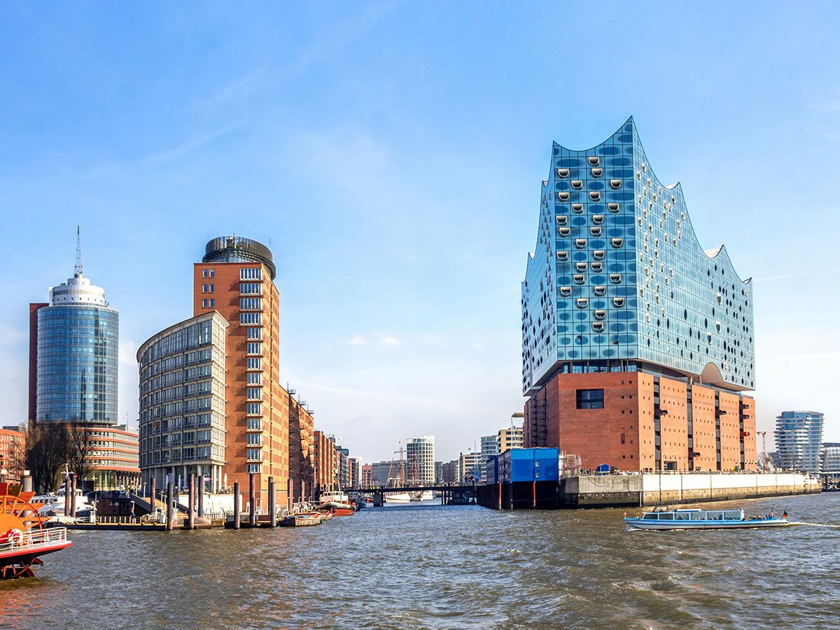 Panoramablick auf die Elbphilharmonie und moderne Gebäude am Hamburger Hafen bei strahlend blauem Himmel.