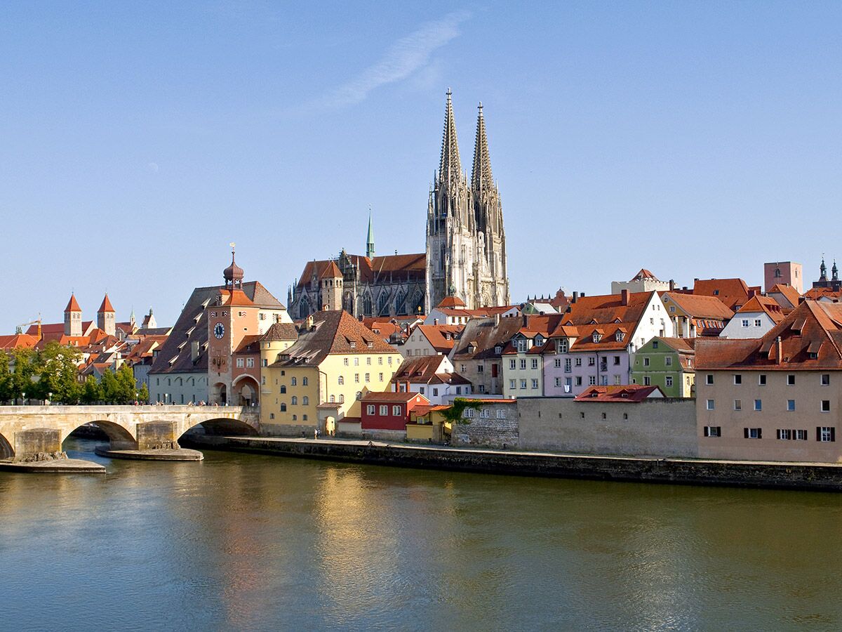 Regensburg Panorama mit Dom, Steinerner Brücke über Donau und bunten Häusern der Altstadt bei Sonnenschein.