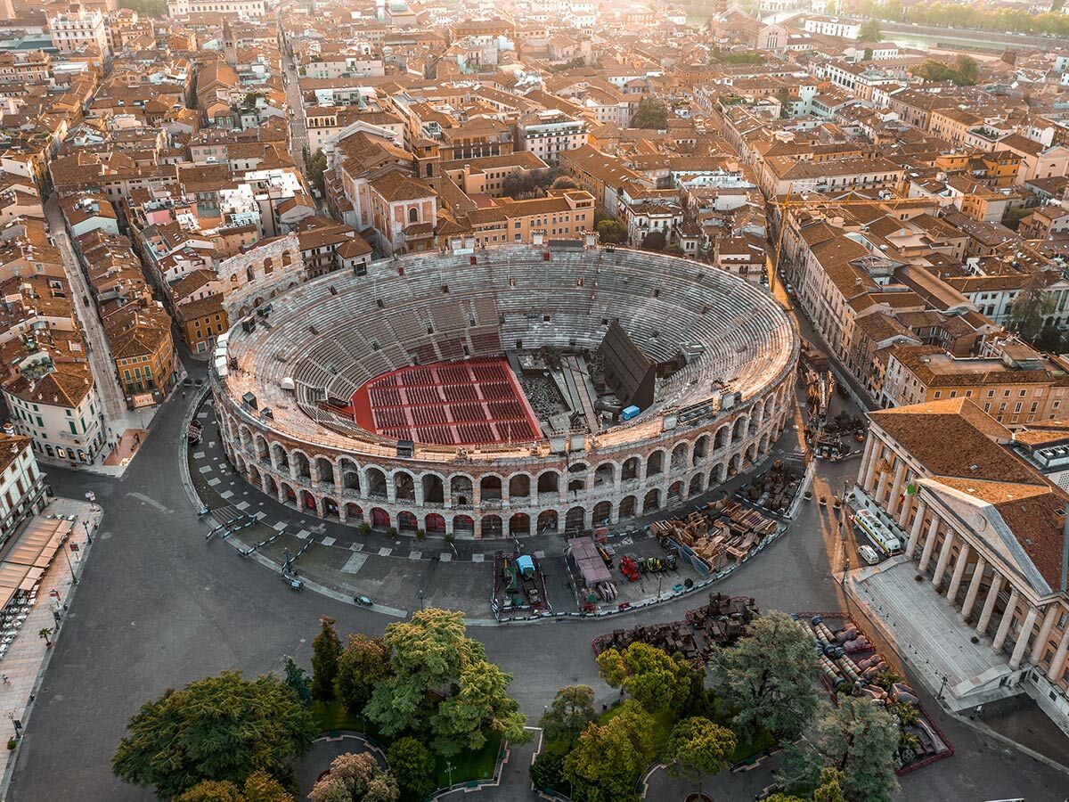 Antike römische Arena von Verona aus der Luft bei Sonnenuntergang, umgeben von historischen Gebäuden.