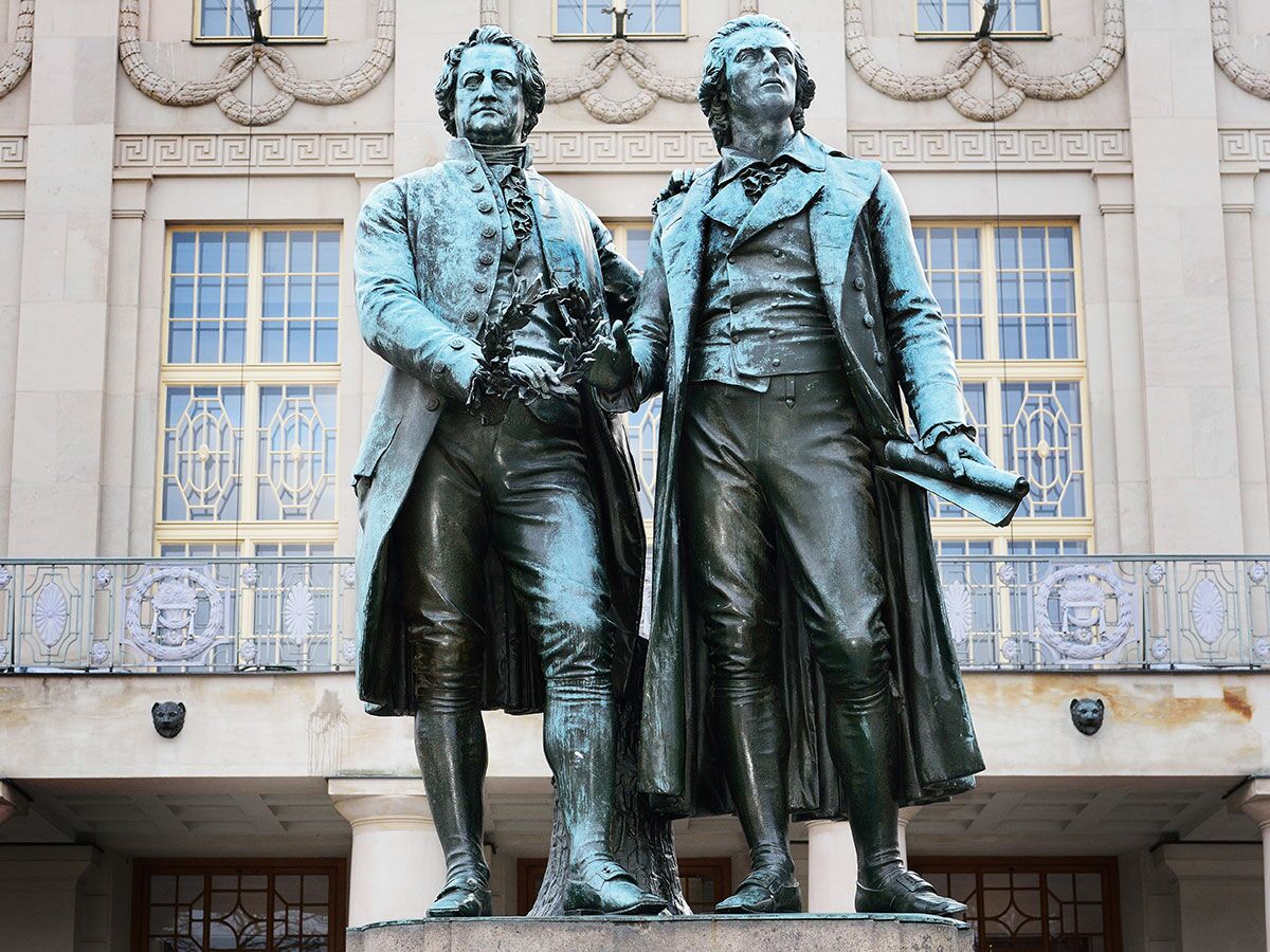 Das Goethe- und Schiller-Denkmal in Weimar, eine Bronzeskulptur der beiden deutschen Dichter vor einem historischen Gebäude.