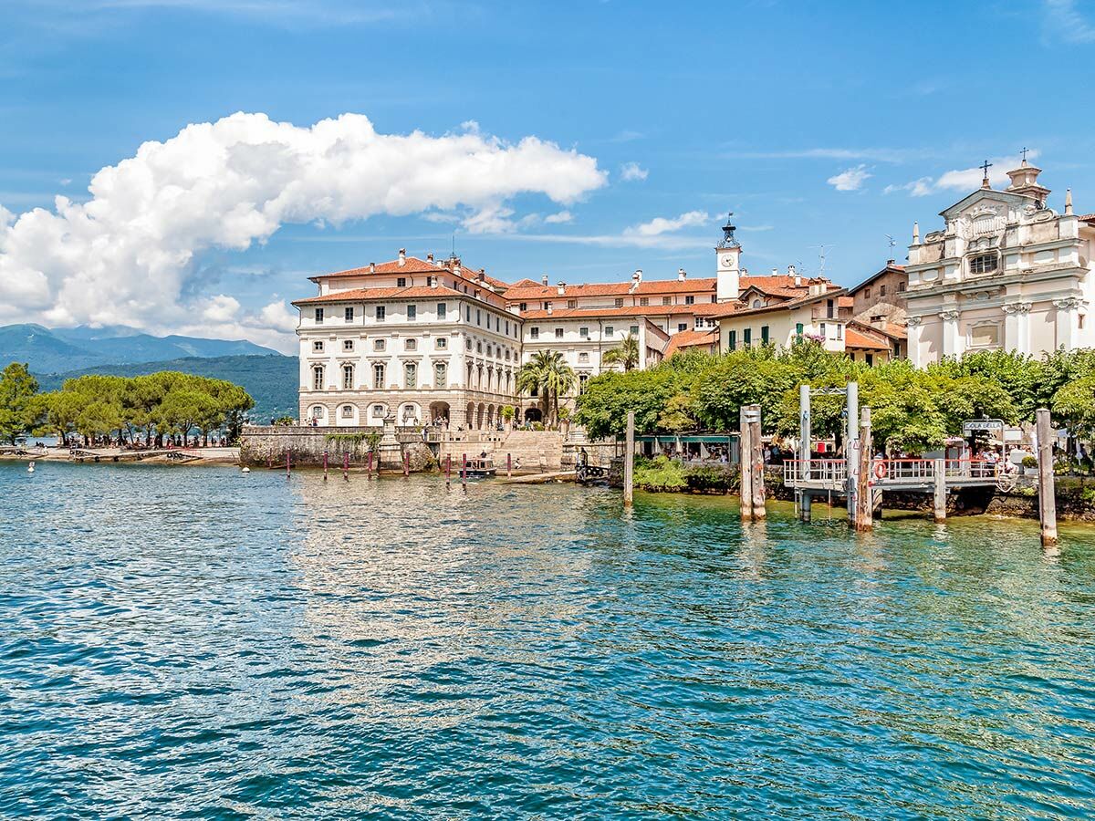 Panoramablick auf Isola Bella am Lago Maggiore mit dem Borromäischen Palast, Kirche und blauem See im Sommer.