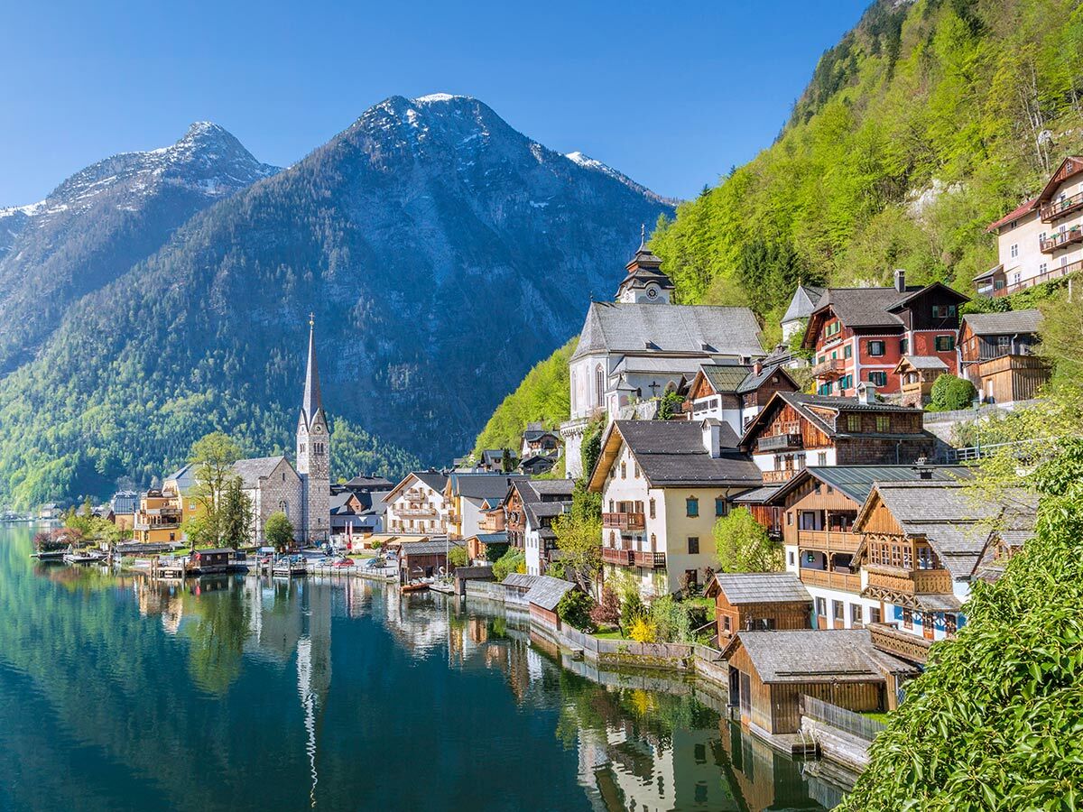 Malerisches Dorf Hallstatt, Österreich, am See. Traditionelle Häuser, Kirchturm und schneebedeckte Alpen im Hintergrund.