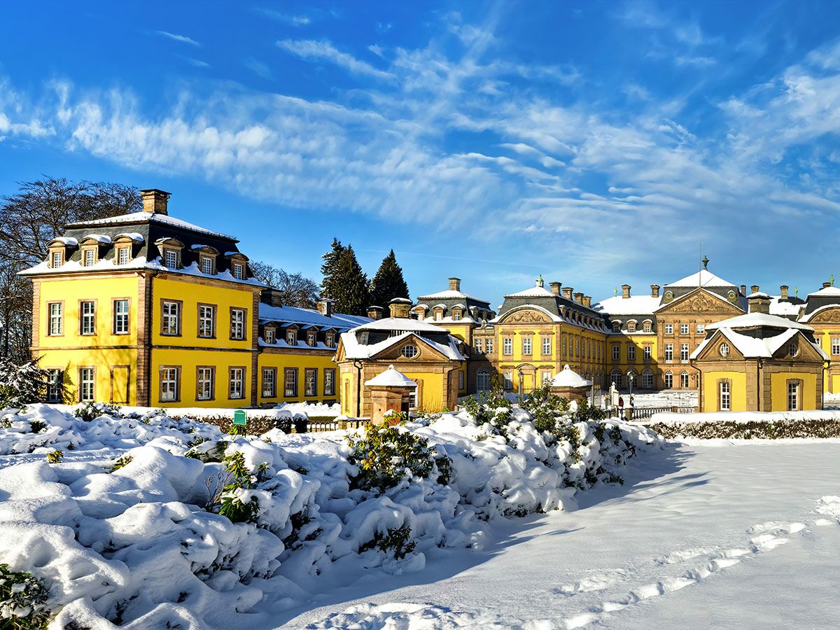 Barockes Schloss Bruchsal in Baden-Württemberg im Winter, strahlend gelb mit Schnee und blauem Himmel.