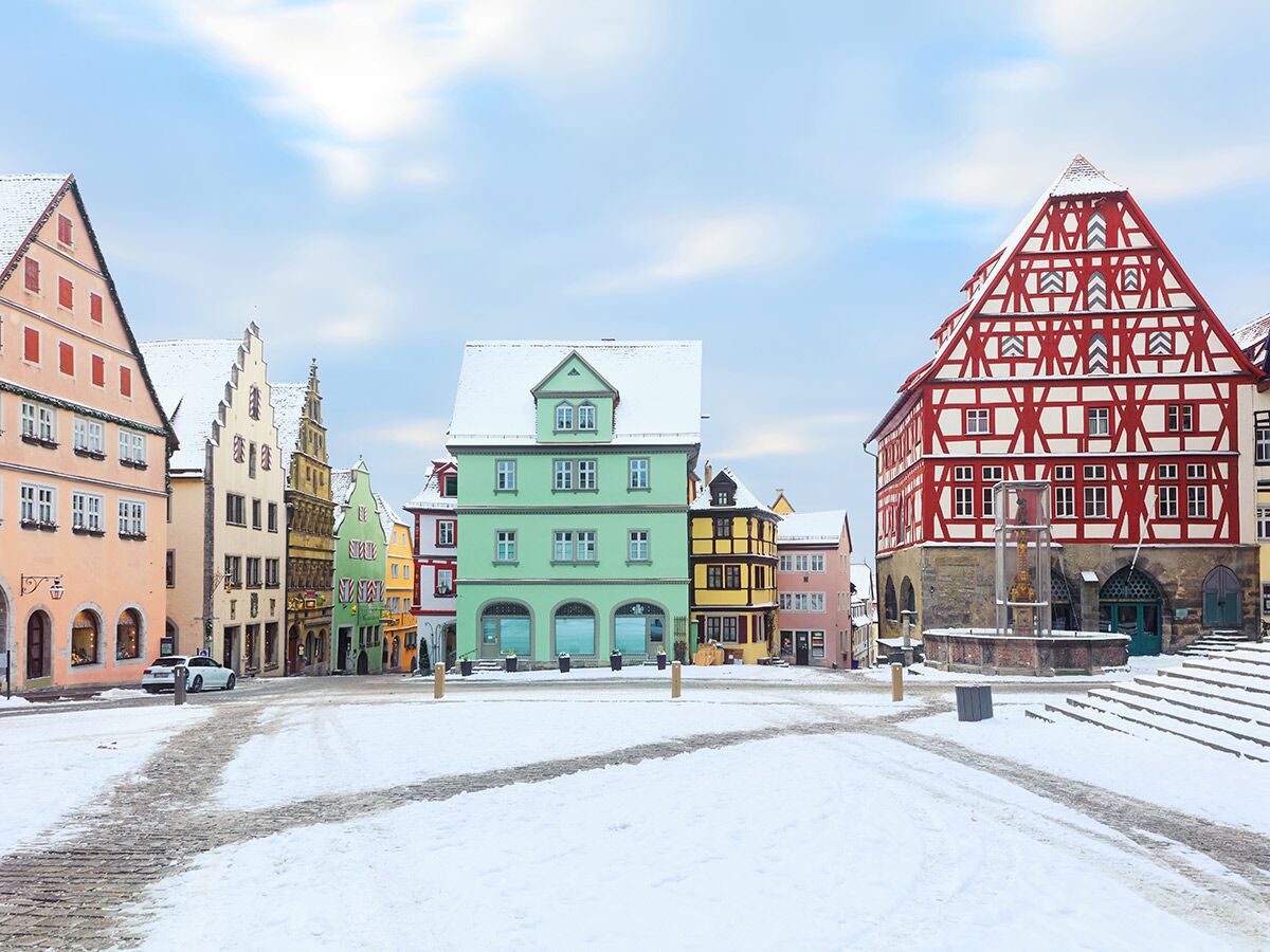 Verschneiter Marktplatz in Rothenburg ob der Tauber mit bunten, historischen Fachwerkhäusern im Winter.