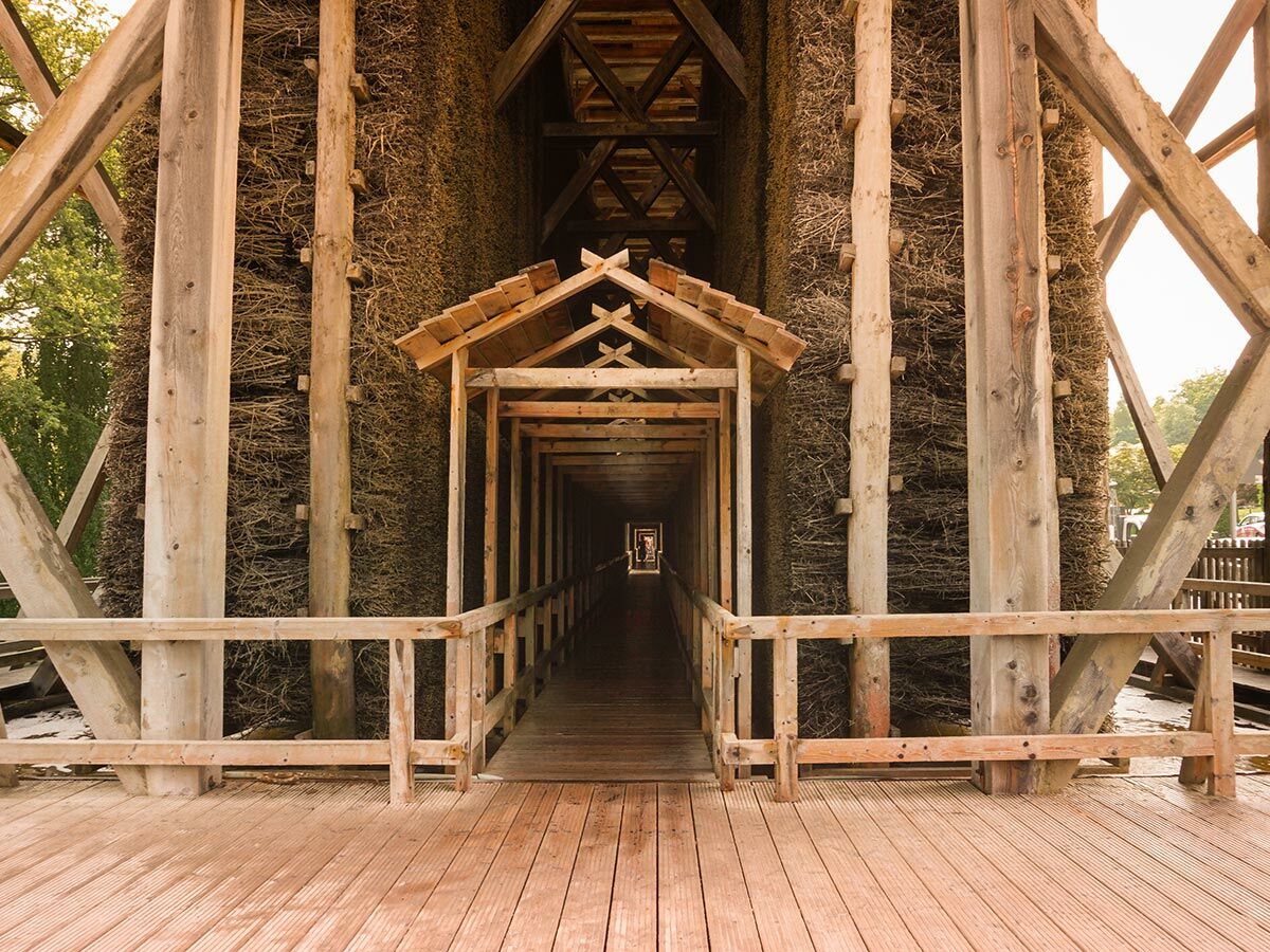Blick in ein Gradierwerk mit langem Holztunnel, umgeben von Reisigwänden und stabilen Holzbalken. Historisches Sole-Bauwerk.