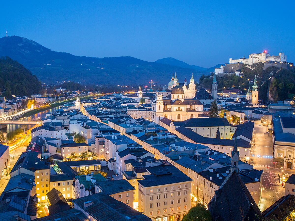 Panoramablick auf die historische Stadt Salzburg bei Nacht. Beleuchtete Festung Hohensalzburg über Salzburger Dom und Salzach.