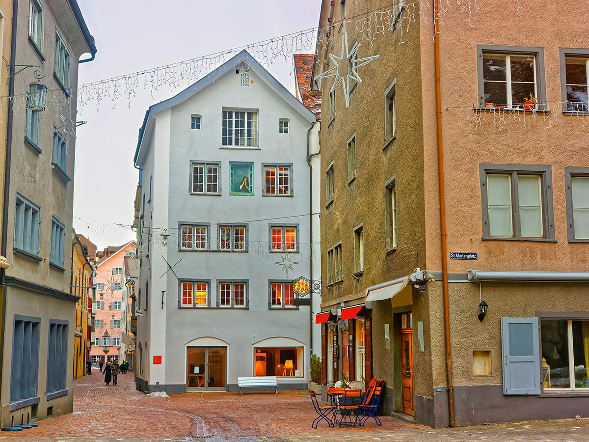 Malerische Altstadtgasse mit historischen Gebäuden, bunten Fassaden und Lichterketten bei Dämmerung in St. Martinsplatz.
