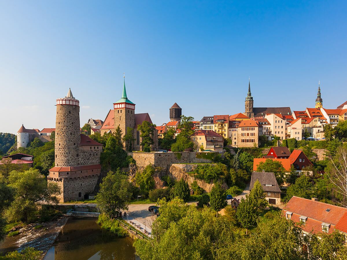 Historische Altstadt Bautzen in Sachsen mit Ortenburg, Kirchen und malerischen Häusern am Fluss Spree unter blauem Himmel.