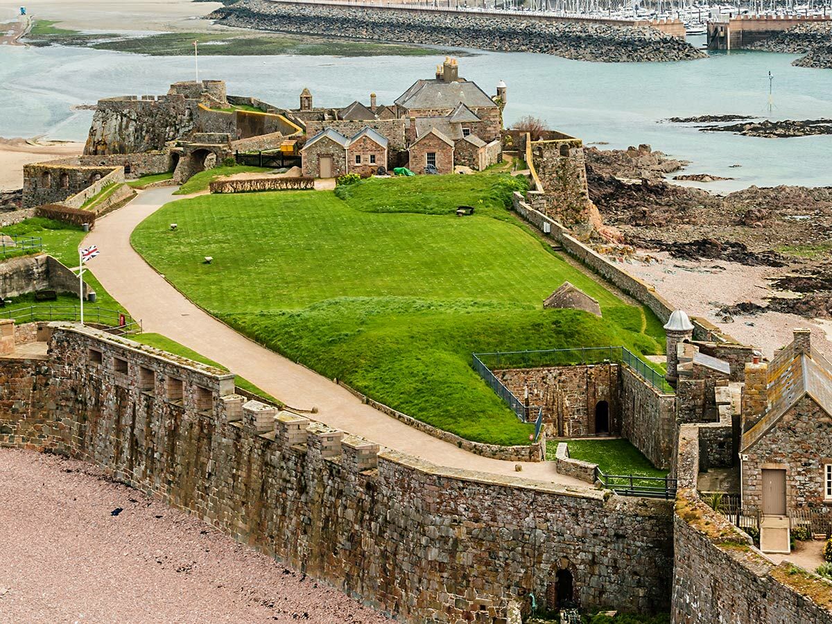 Luftaufnahme der Elizabeth Castle Festung auf Jersey mit steinernen Mauern, grünem Rasen, Wegen und dem Meer im Hintergrund.