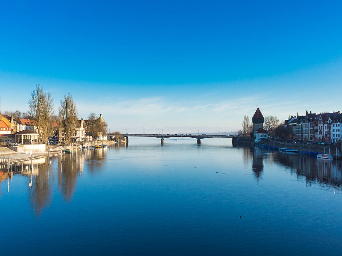Panoramablick Lindau, Bodensee. Historische Brücke, Mangturm, Uferbebauung, blauer Himmel, Winterstimmung.