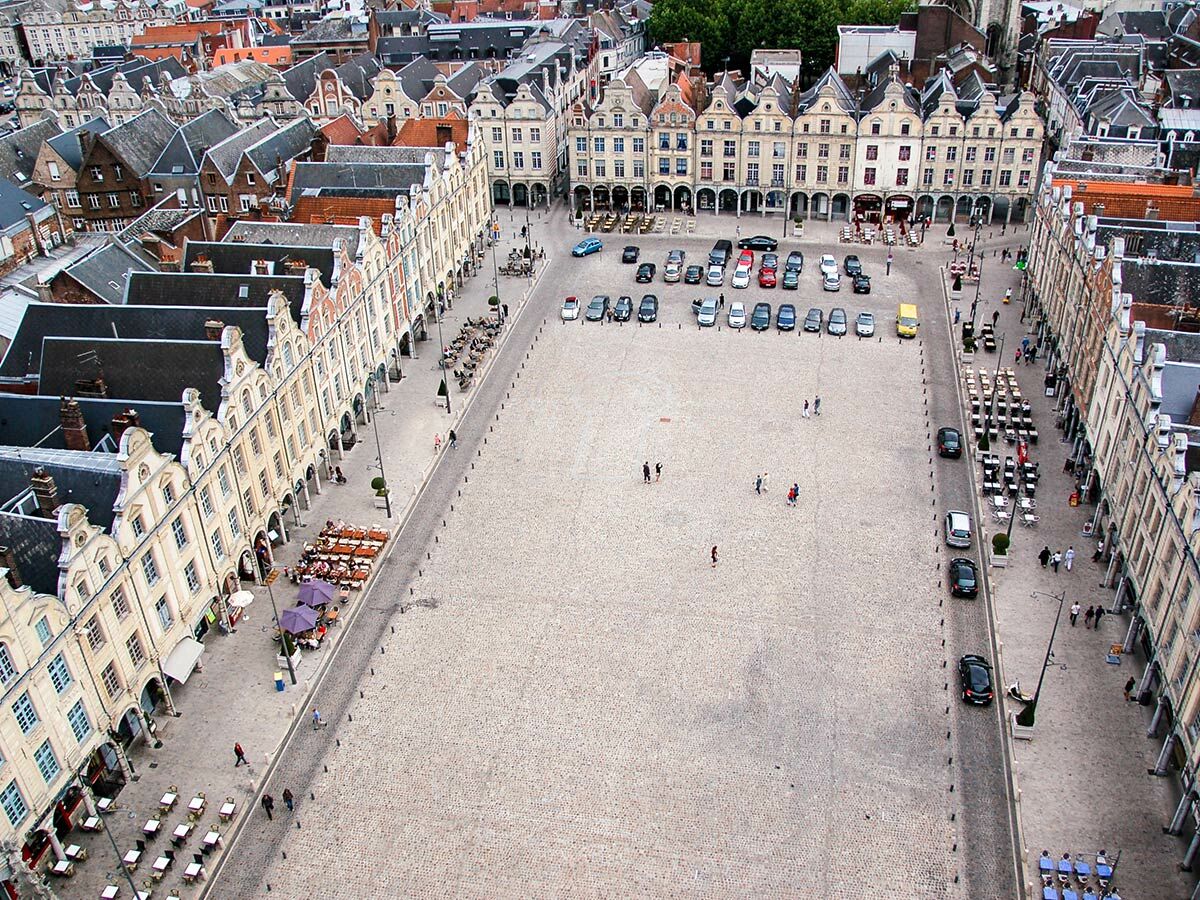 Vogelperspektive des historischen Marktplatzes in Arras, Frankreich, mit flämischen Giebelhäusern, Menschen und Autos.