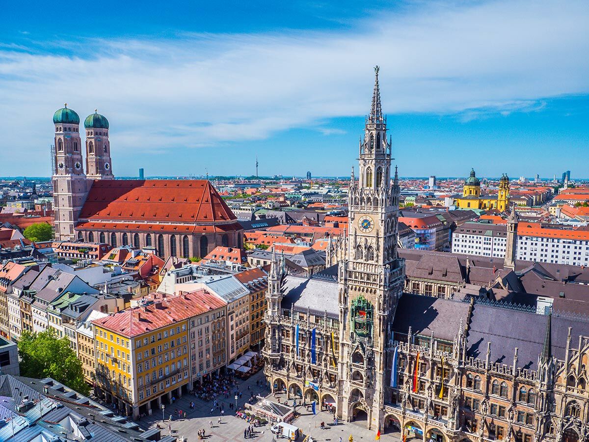 Luftaufnahme Münchens mit Frauenkirche, Neuem Rathaus und Marienplatz unter blauem Himmel.