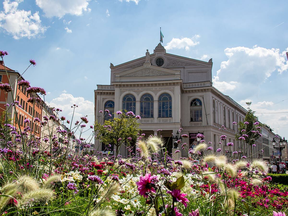 Historisches Gerhart-Hauptmann-Theater in Görlitz, Deutschland, mit farbenprächtigen Blumenbeeten im sonnigen Stadtzentrum.