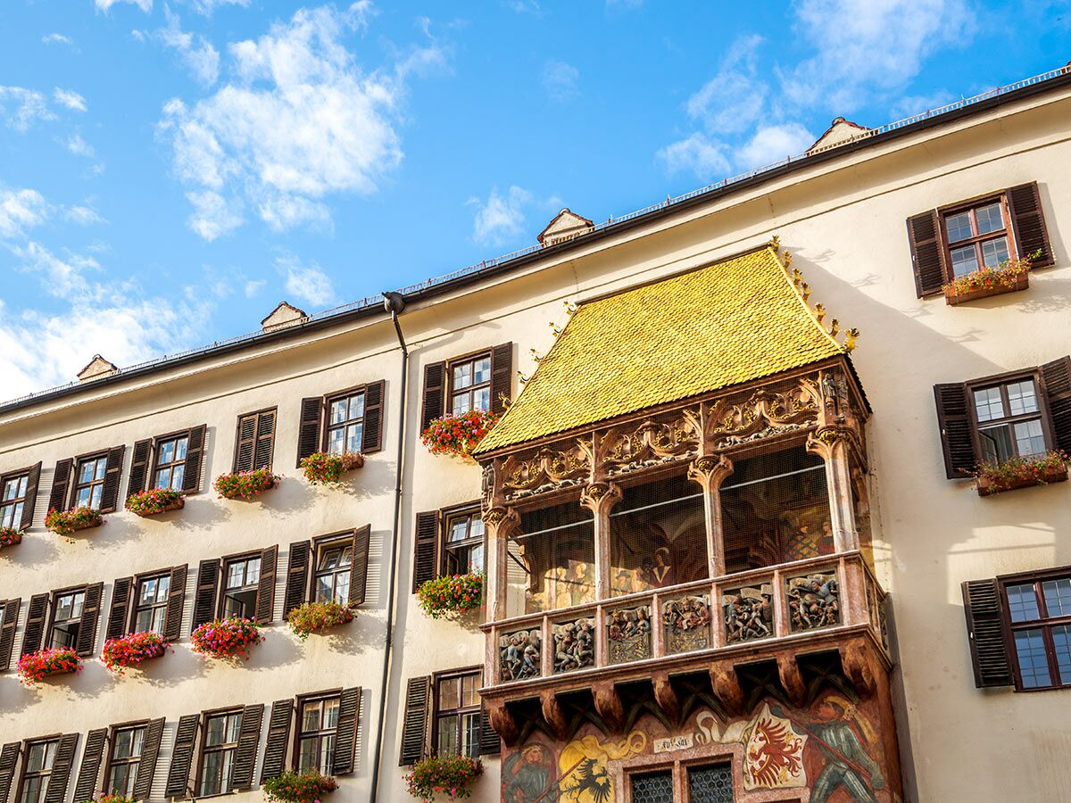 Das Goldene Dachl in Innsbruck, Österreich, mit seinem berühmten goldenen Balkon, Fenstern mit Blumenkästen und blauem Himmel.