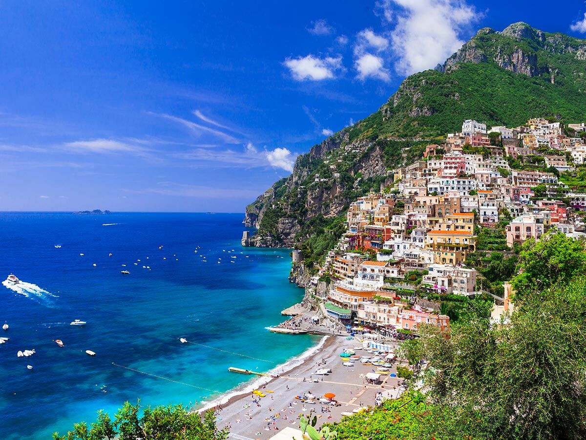 Panoramablick auf Positano, Italien, ein farbenfrohes Dorf an einem steilen Hang mit türkisfarbenem Strand und Mittelmeer.