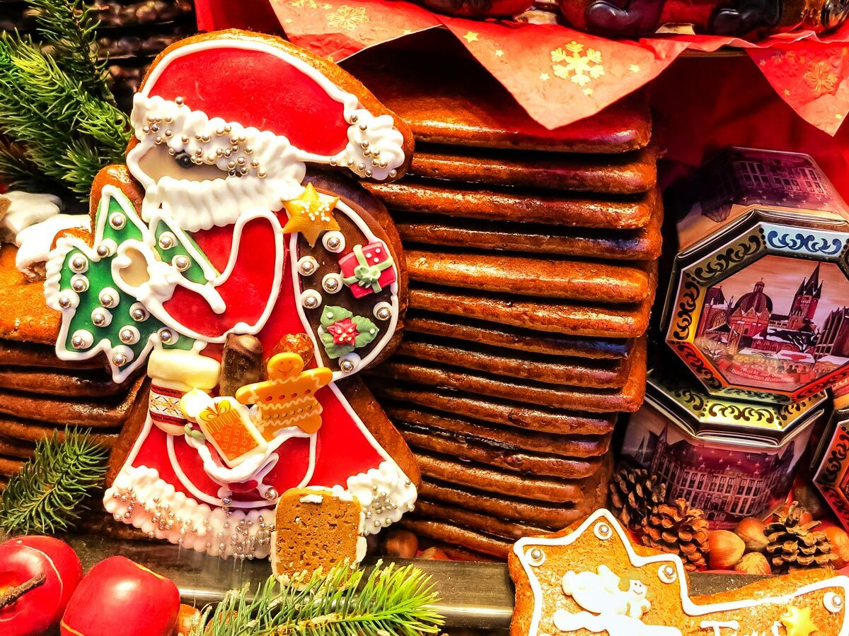 Detailaufnahme eines reich verzierten Lebkuchen-Weihnachtsmanns mit Tannenbaum, Geschenken und weiteren Lebkuchen auf einem Weihnachtsmarkt.