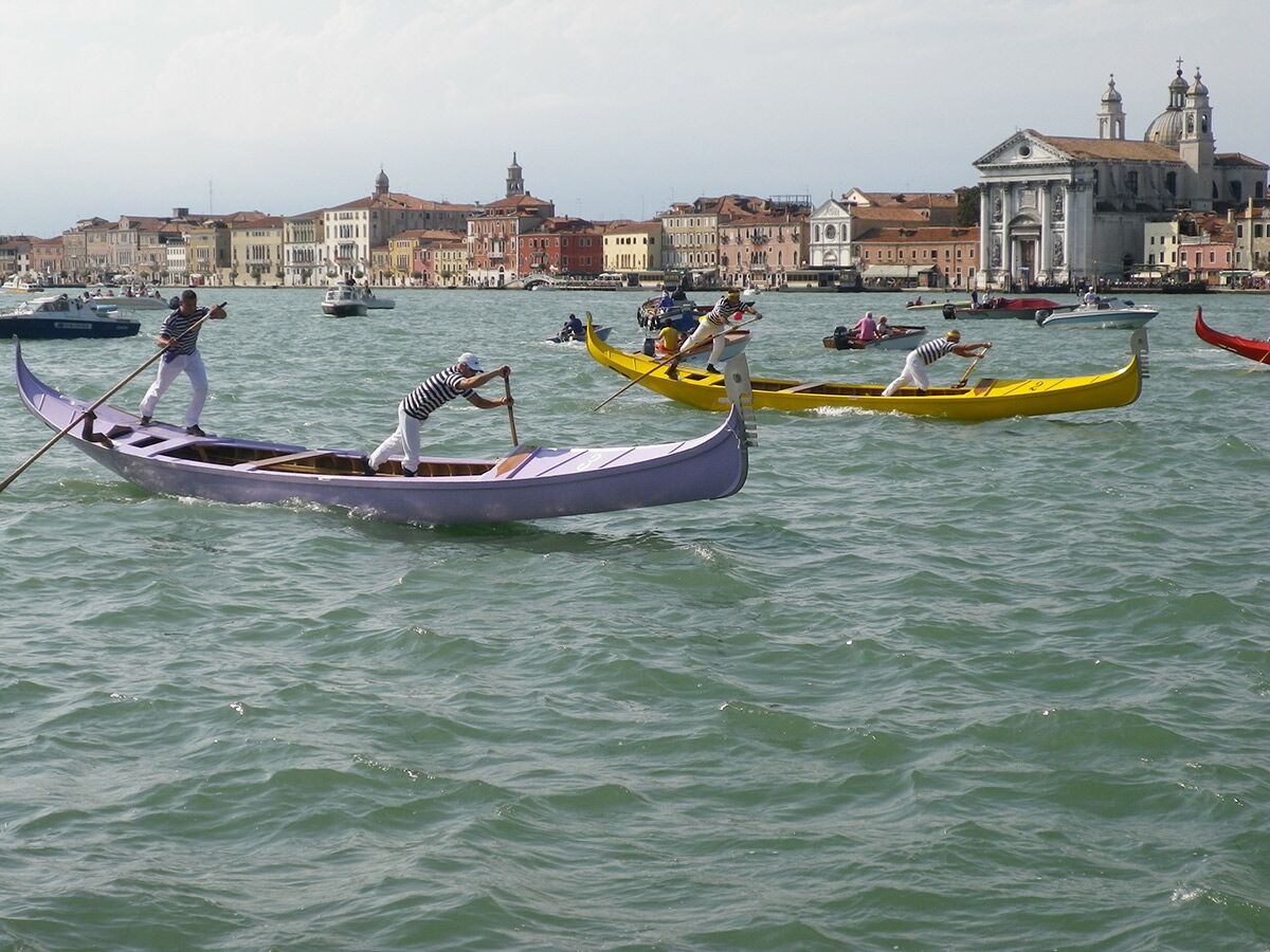 Venedig Regatta mit Ruderern in gestreiften Hemden, die in traditionellen Booten auf dem Wasser um historische Gebäude wetteifern.