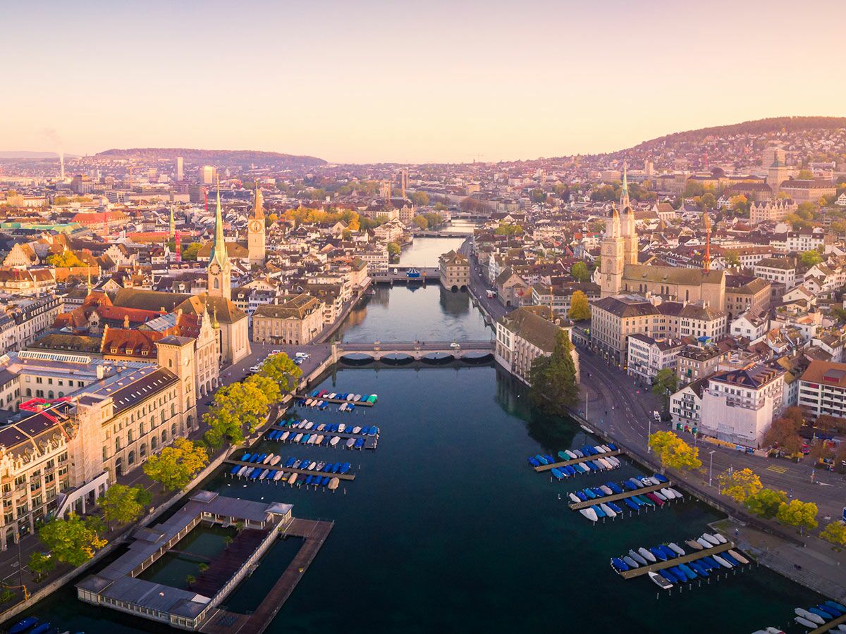 Luftbild Zürich bei Sonnenuntergang mit Limmat Fluss, Fraumünster, Grossmünster, St. Peter Kirche, Brücken und Yachthafen.