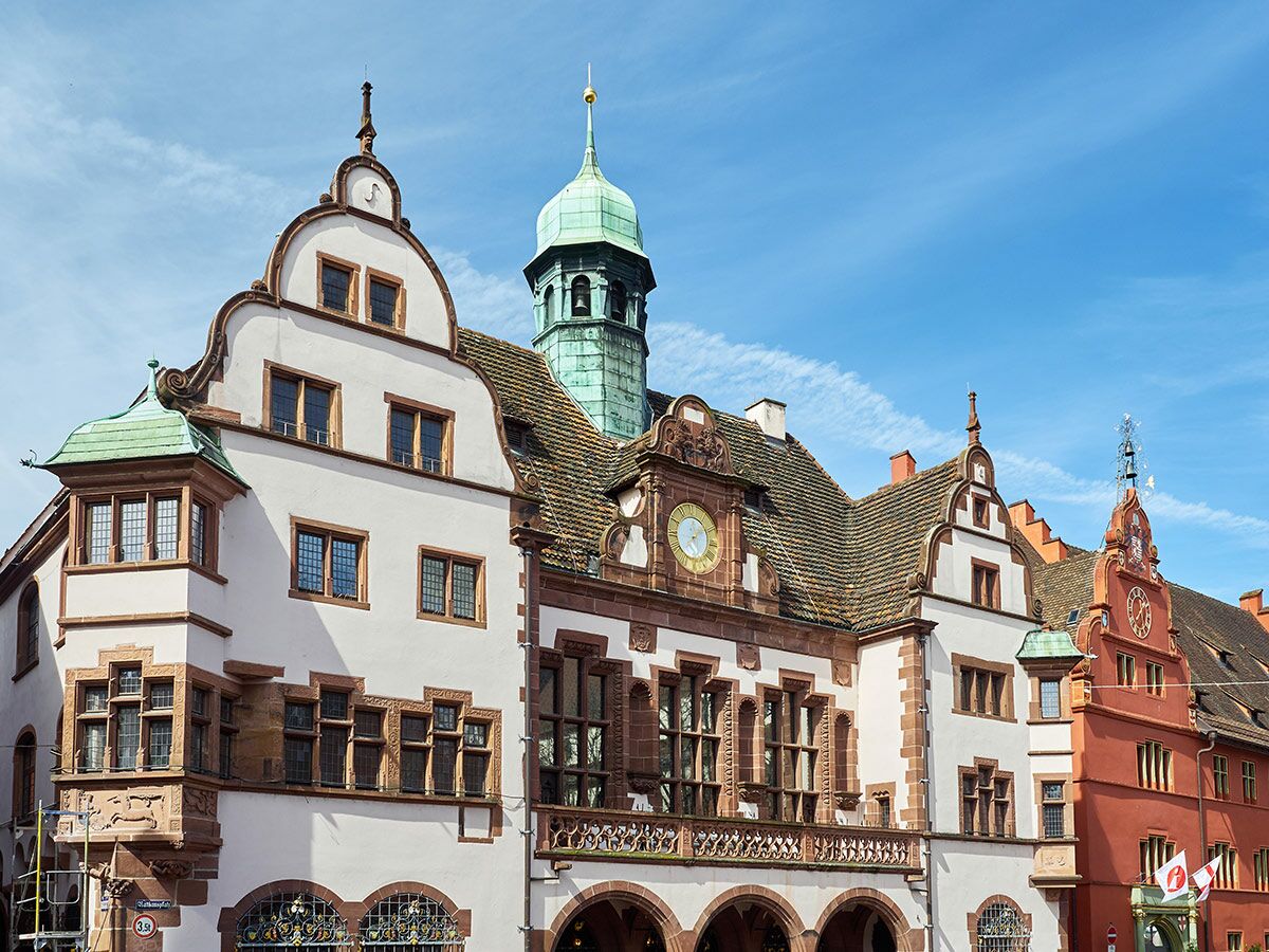Detailansicht des historischen Rathauses mit aufwendigen Giebeln, prominentem Turm und Uhr unter blauem Himmel.