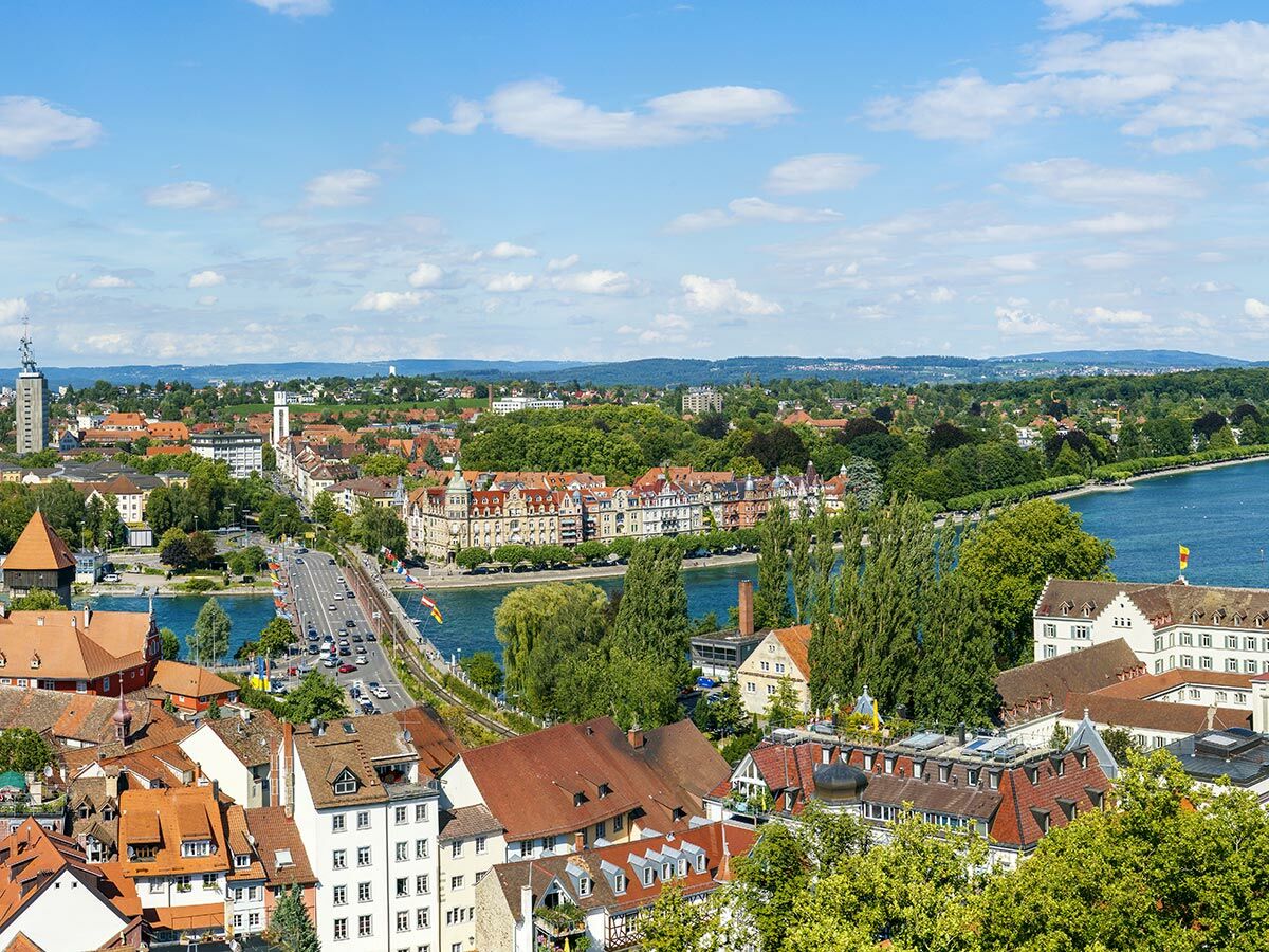 Luftaufnahme von Konstanz am Bodensee mit Seerheinbrücke, historischen Gebäuden, grünen Ufern und blauem Himmel.