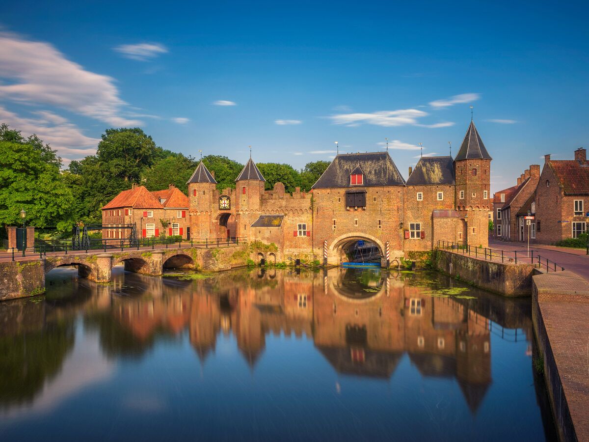 Historisches Koppelpoort Stadttor in Amersfoort, Niederlande, mit Ziegelmauern, Türmen, Brücken und Wasser. Spiegelung im Kanal.