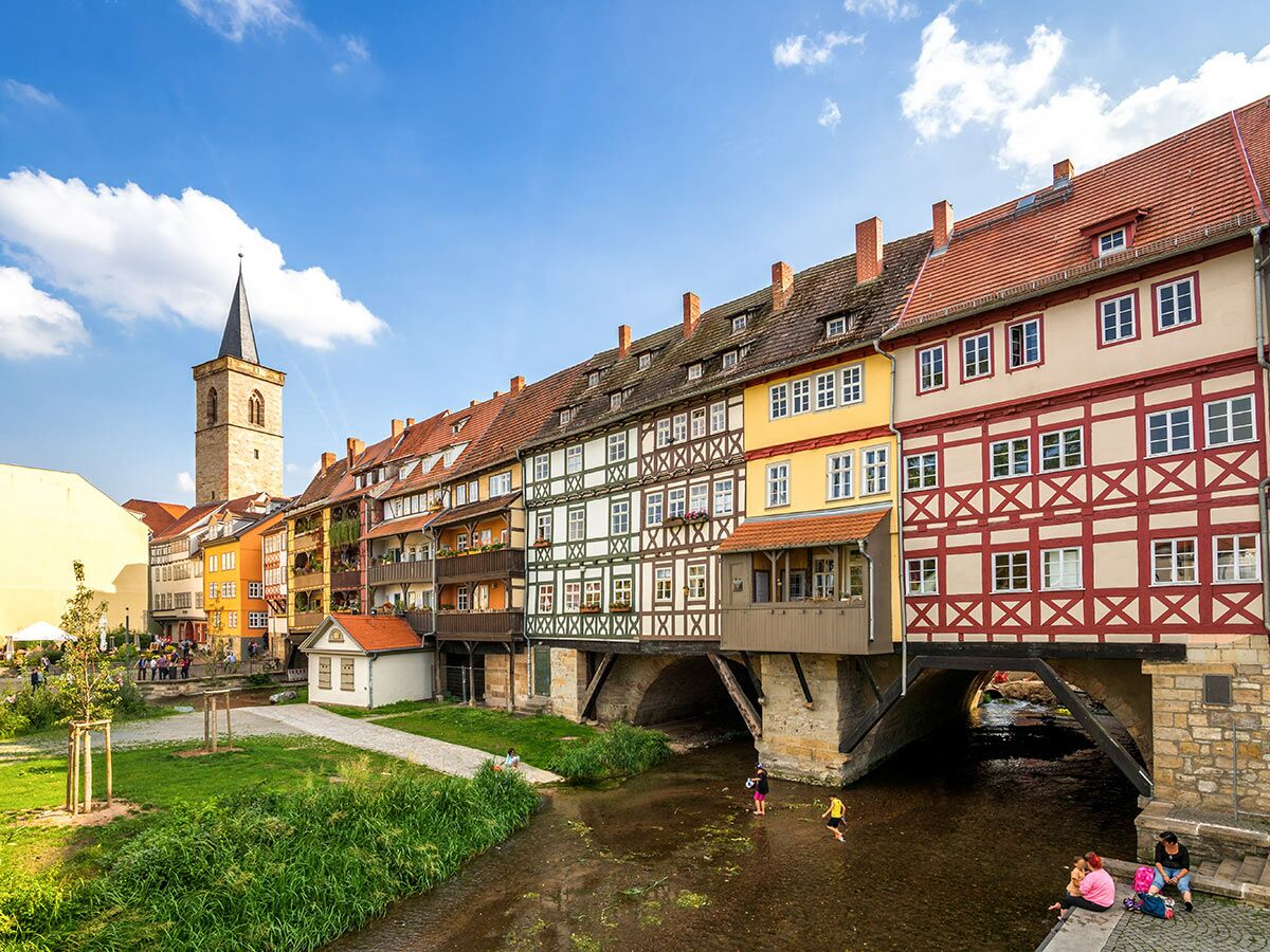 Historische Krämerbrücke in Erfurt mit bunten Fachwerkhäusern über dem Fluss Gera an einem sonnigen Tag.