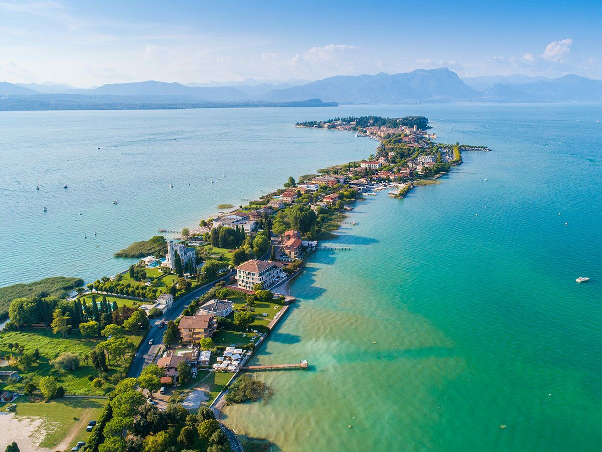 Luftbild von Sirmione am Gardasee, Italien, mit langgestreckter Halbinsel, historischen Gebäuden und türkisblauem Wasser.