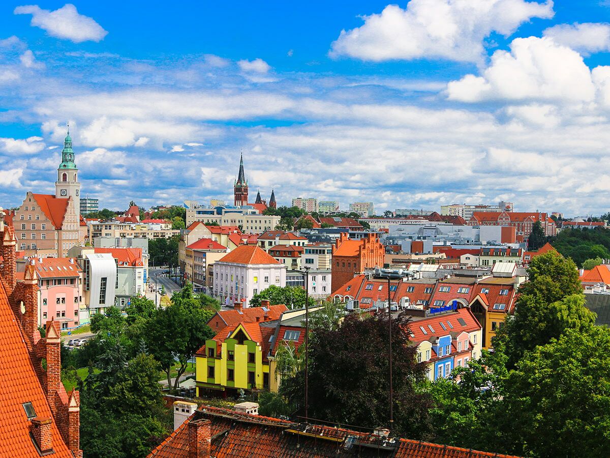 Panoramablick auf die historische Stadt Legnica in Polen mit Kathedrale, Kirchtürmen, roten Dächern unter blauem Himmel.