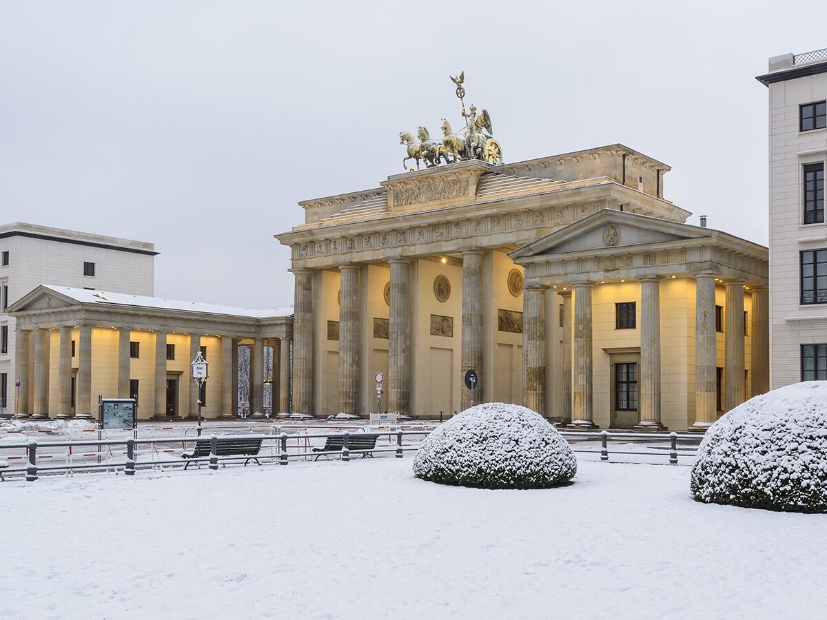 Das Brandenburger Tor in Berlin im Winter, bedeckt mit Schnee, historische Architektur und die Quadriga.