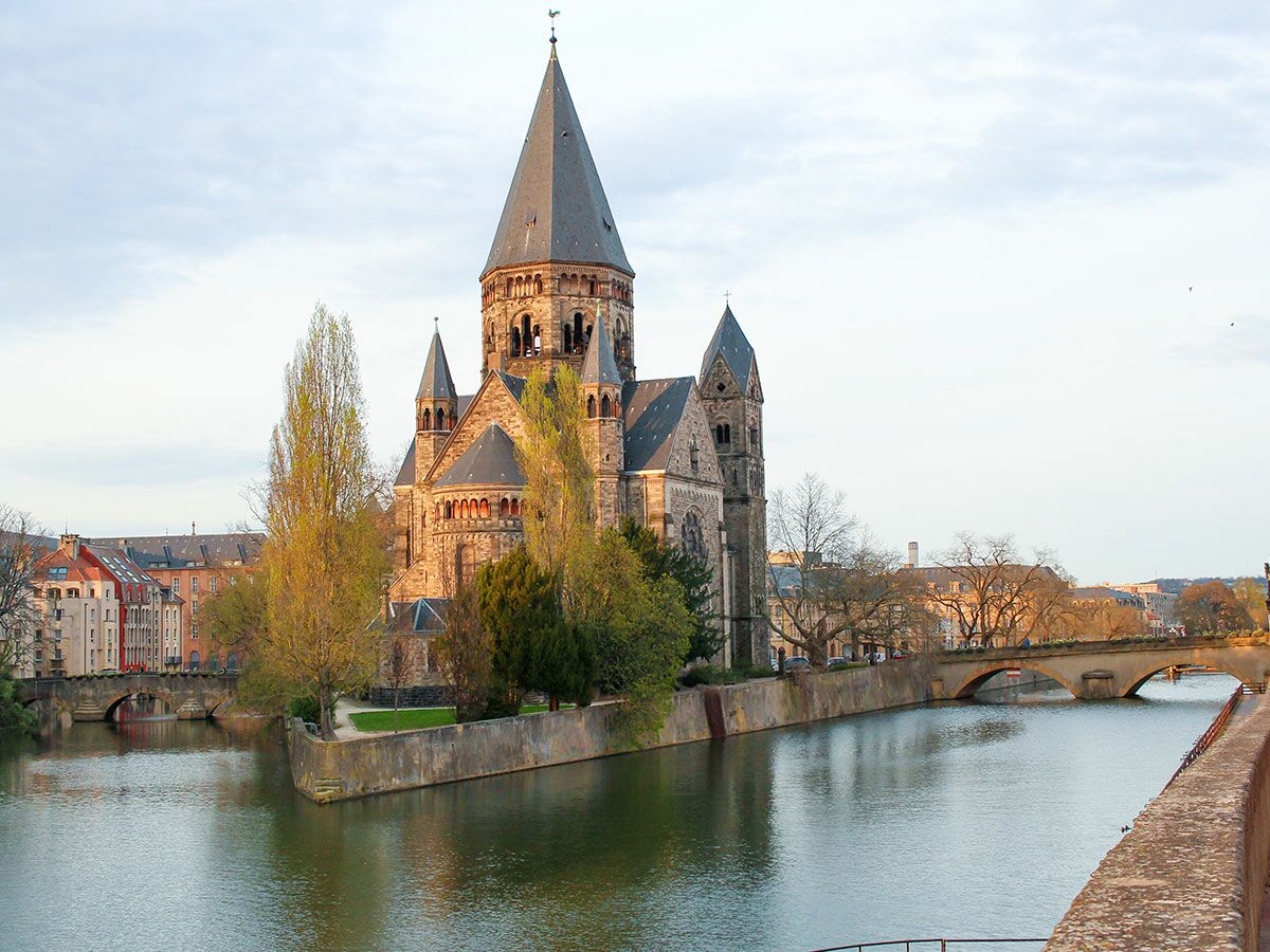 Der historische Temple Neuf in Metz steht auf einer Insel der Mosel, umgeben von Brücken und Gebäuden.