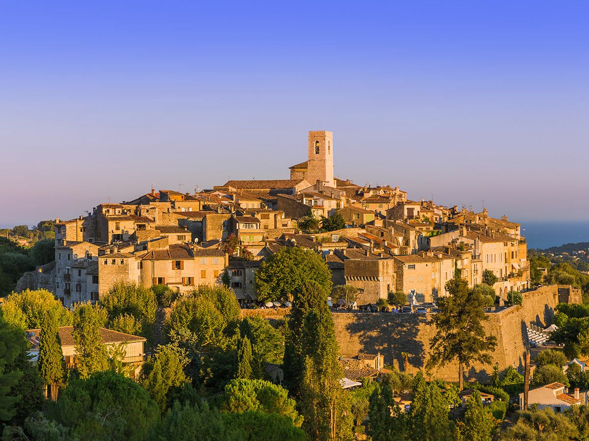 Saint-Paul-de-Vence, malerisches mittelalterliches Bergdorf an der Côte d'Azur, Steinhäuser, Glockenturm, Bäume, goldenes Licht, Meerblick.