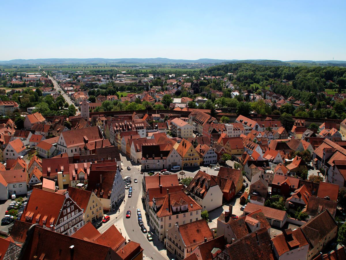 Panoramablick über eine historische deutsche Altstadt mit roten Dächern und einer Stadtmauer an einem sonnigen Tag.