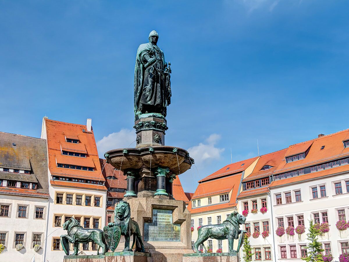 Detailansicht des Gerechtigkeitsbrunnens in Görlitz mit Skulptur von Kaiser Ferdinand I., Löwenfiguren und historischen Gebäuden.